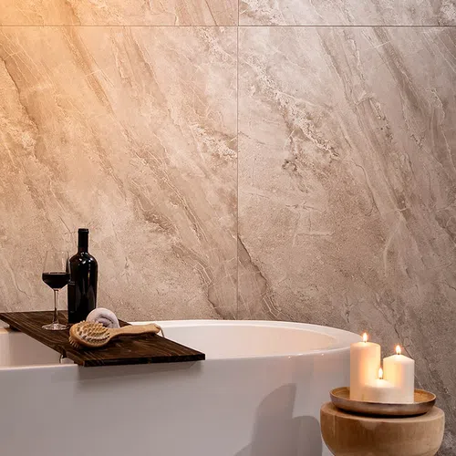 Relaxing bathroom scene with white bathtub, wooden tray holding wine and brush, and lit candles on stool.