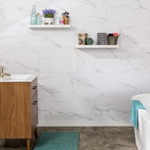Modern bathroom with wood vanity, white marble tile wall, floating shelves, and teal bath mat and towel.