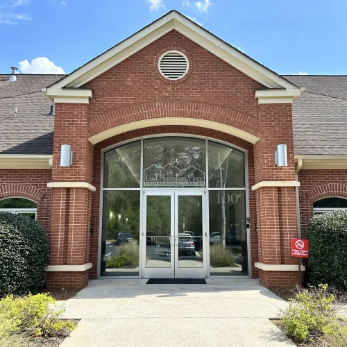 Entrance to Lost Mountain Place Professional Center with large glass doors and red brick exterior on a sunny day