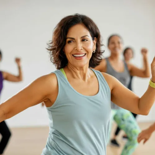 Smiling middle-aged woman in light blue tank top exercising in a fitness class with others in the background