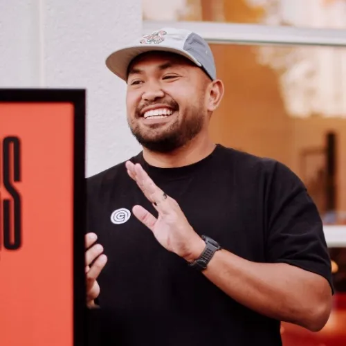 Two men standing next to a Black Runners Joy Gallery sign outside a building with large windows reflecting warm light.