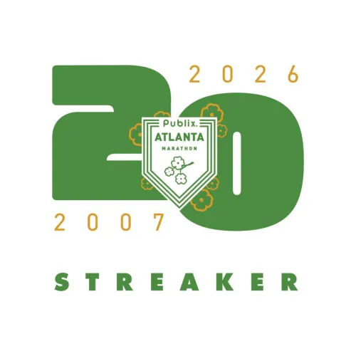 Runners starting the Publix Atlanta Marathon Weekend under green banners on a city street at dawn.