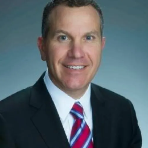 a man wearing a suit and tie smiling at the camera