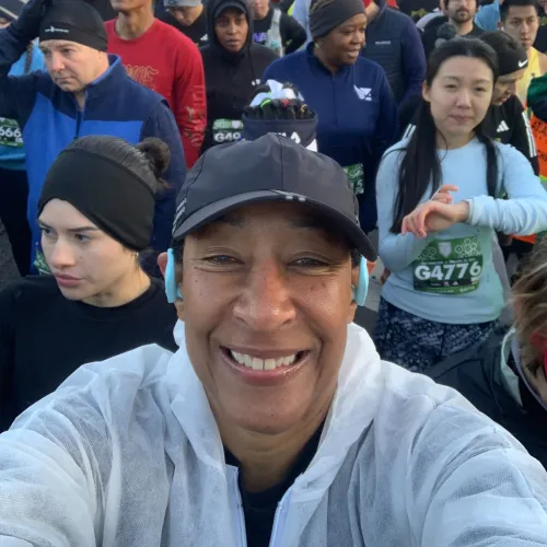 Smiling diverse group of runners gathered at race starting line outdoors in cool weather.