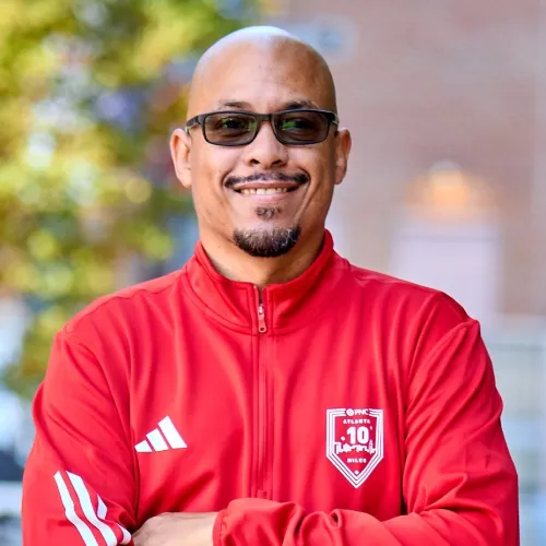 a man wearing a red shirt and sunglasses with his arms crossed