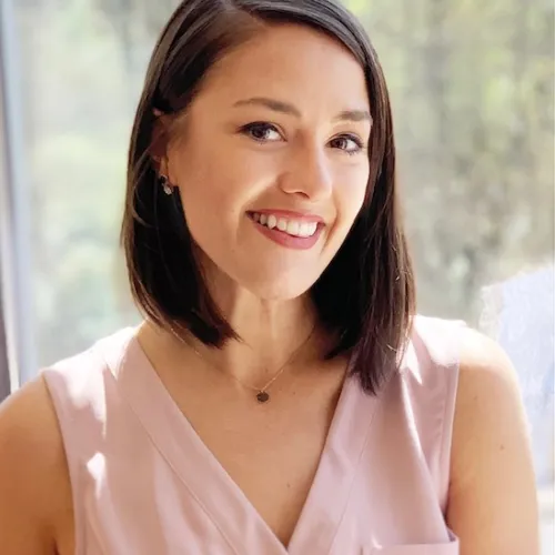 a woman smiling in front of a red wall