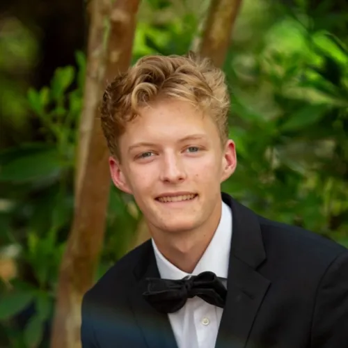 a man in a suit and bow tie sitting on a bench