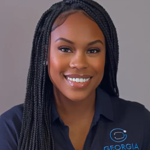 Smiling woman with long braided hair wearing a Georgia Interventional Medicine polo shirt against gray background