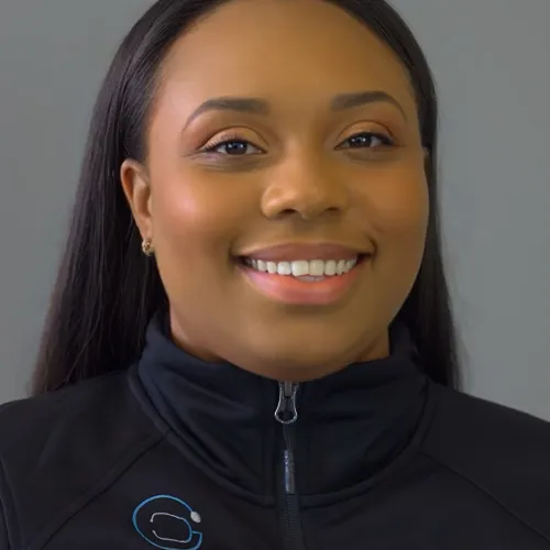 Smiling doctor wearing a white coat and tie, against a gray background.