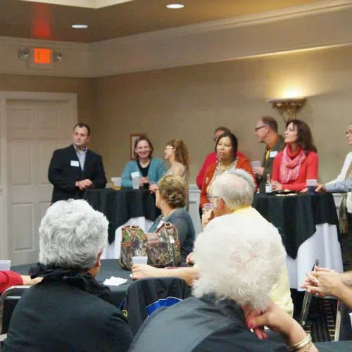 Business networking event with professionals attentively listening to a speaker in a conference room.