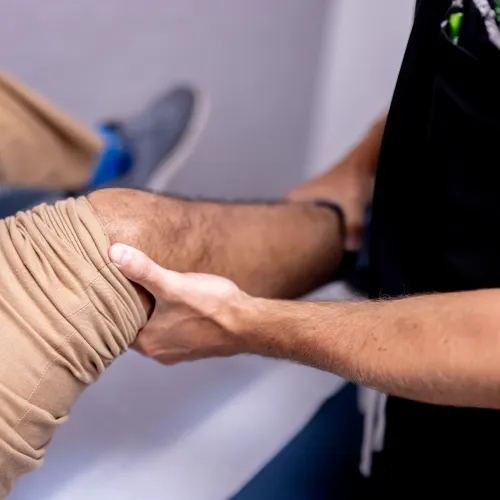Physical therapist performing knee rehabilitation exercises by supporting patient's bent leg.