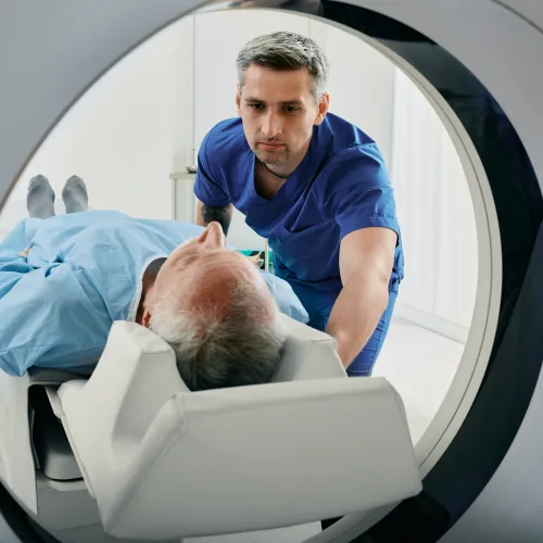 A healthcare professional assists a patient during a CT scan procedure in a medical facility.