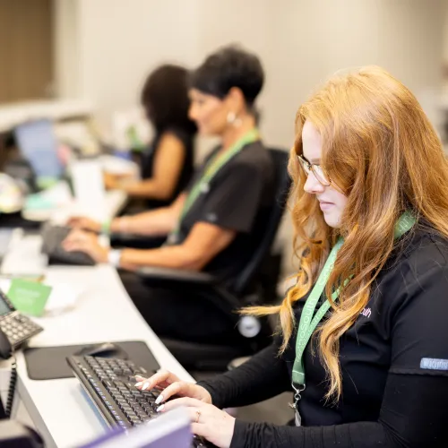 Focused professionals working at reception desks with computers in a modern office environment.