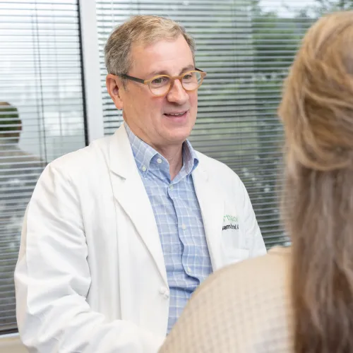 A doctor in a white coat engages with a patient during a consultation in a bright office.
