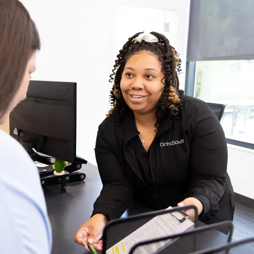 A friendly employee assisting a customer at a service desk with documents in hand.