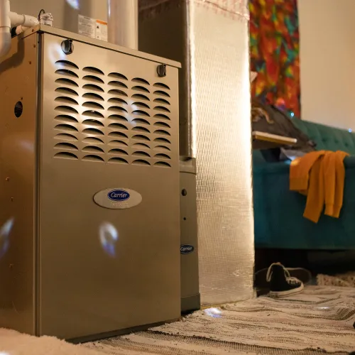 Indoor Carrier brand furnace next to a drum set and cozy living area with teal sofa and colorful wall art.