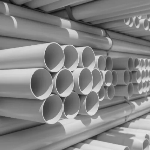 Stacks of white PVC pipes neatly arranged in rows in a warehouse or storage area.