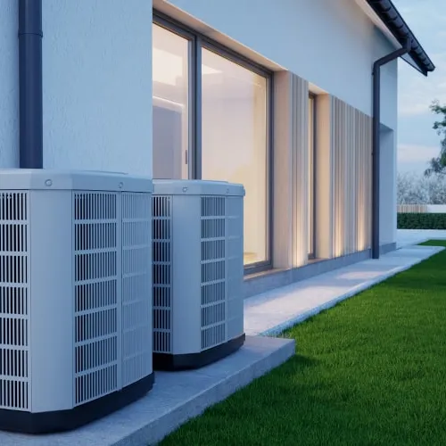 Two outdoor air conditioning units installed beside a modern house with large windows and green lawn.