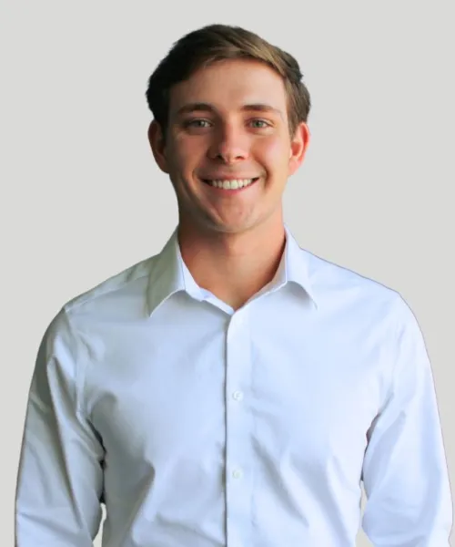 Smiling young man in a white shirt against a neutral background, radiating confidence and positivity.