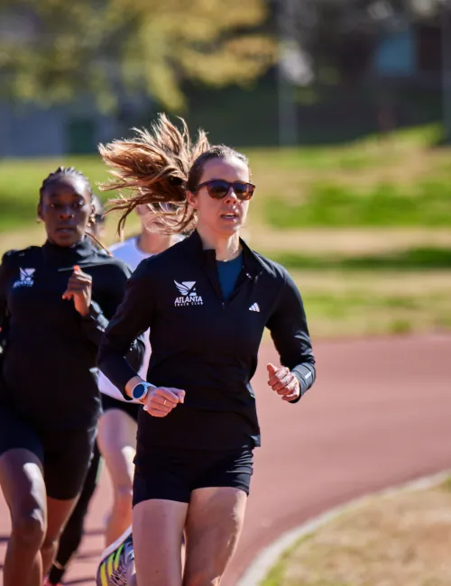 a group of women running on a dirt road