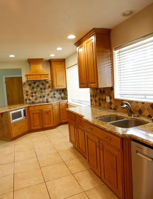 Modern kitchen with wooden cabinets, granite countertops, stainless steel appliances, and tiled floor and backsplash.