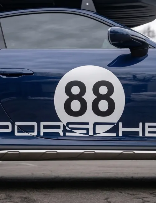 Side view of a blue Porsche sports car with number 88 and Porsche logo on the door.