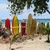 Colorful surfboards lined up on a sandy beach with ocean waves and blue sky in the background