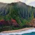 Dramatic green cliffs rising above a sandy beach and ocean waves under a cloudy sky