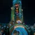 Universal Epic Universe entrance gate illuminated at night with colorful lights and visitors walking through.