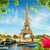 Bright Eiffel Tower by the Seine River with boats, framed by green leaves and pink flowers on a sunny day.