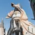 Large dragon sculpture perched on Gringotts Bank building in a theme park under clear blue sky.