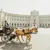 Horse-drawn carriage with tourists passing in front of a grand historic European palace in bright daylight