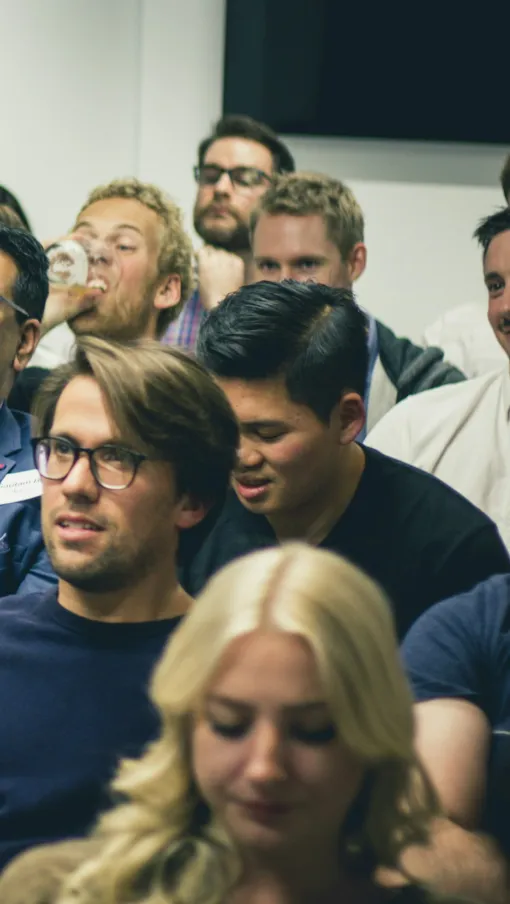 Diverse group of adults smiling and engaged at an indoor seminar or workshop event.