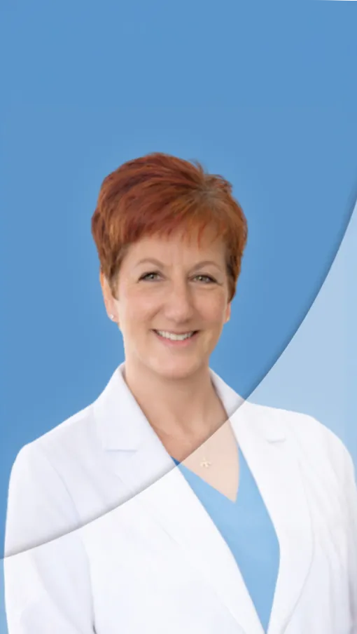 Smiling female healthcare professional wearing a white coat and blue scrubs against a blue background