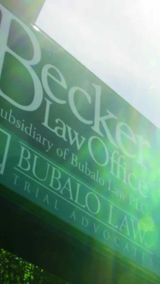 Becker Law Office sign with sun flare and blue sky background in an outdoor setting