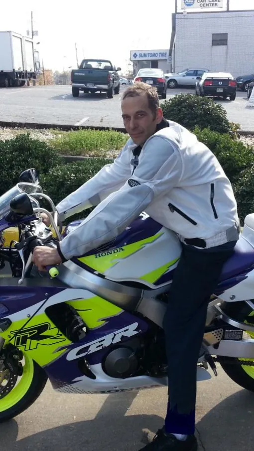 Vinnie sitting on a motorcycle in a parking lot