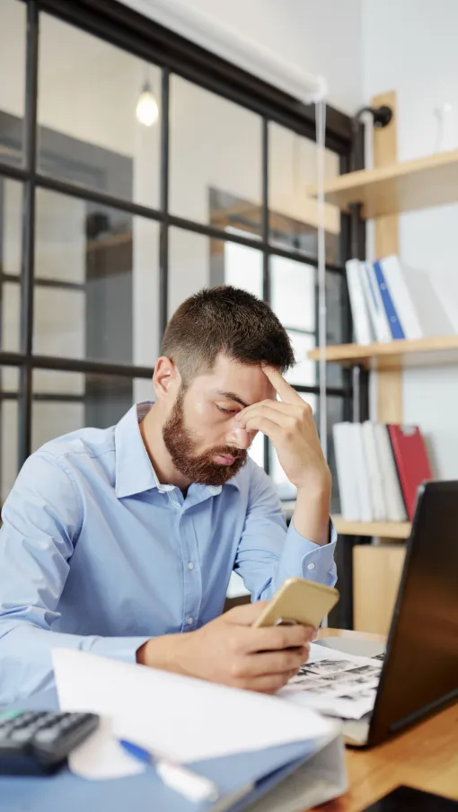 a man sitting at a desk with his hand on his face