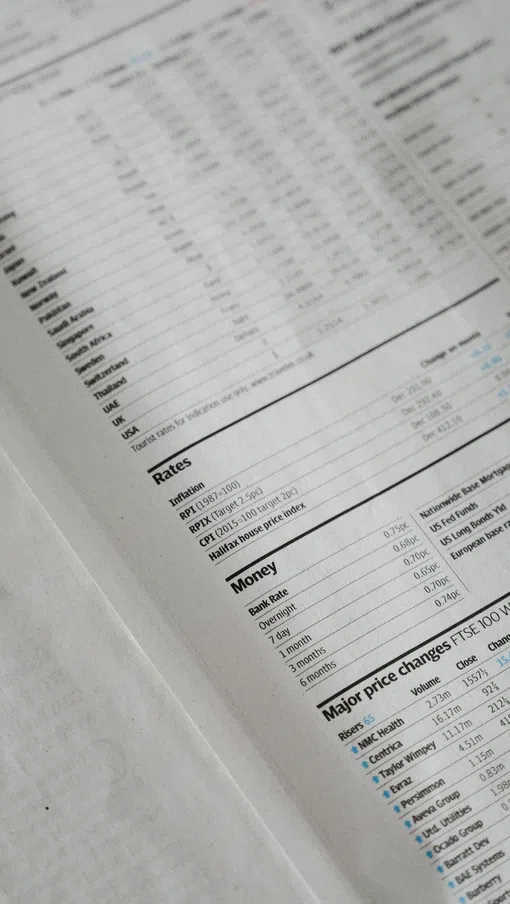 Close-up of financial newspaper pages featuring stock prices, rates, money listings, and price changes.