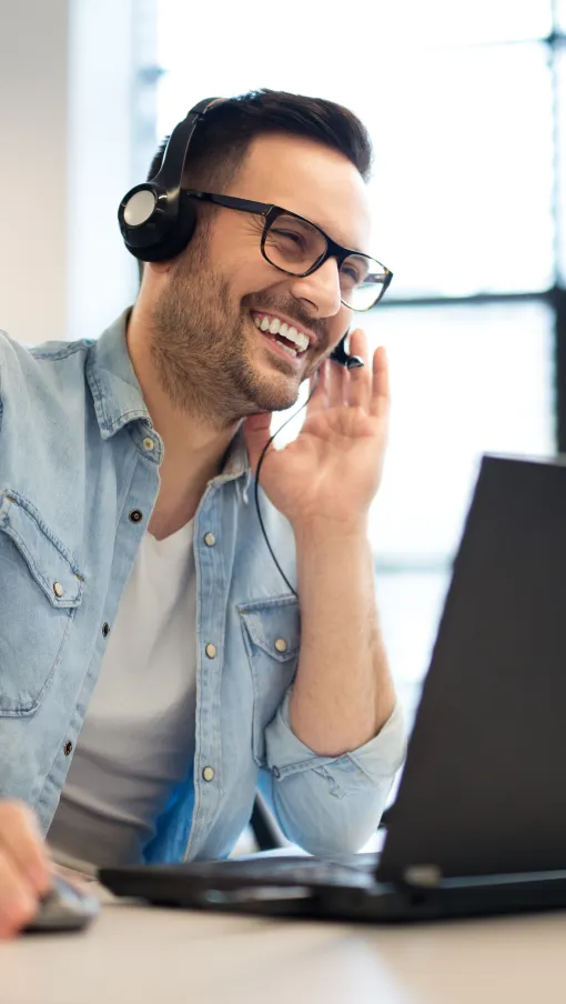 a man wearing headphones and sitting at a desk with a laptop