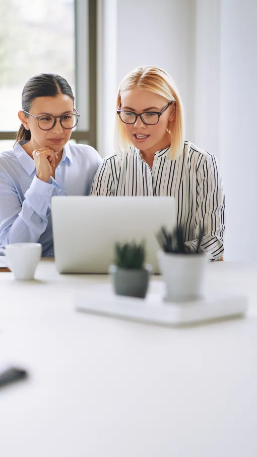 a woman and a man sitting at a table with a laptop