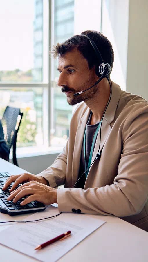 a person wearing headphones and sitting at a desk with a computer