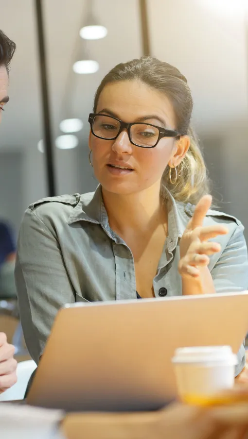 a group of people sitting at a table looking at a laptop