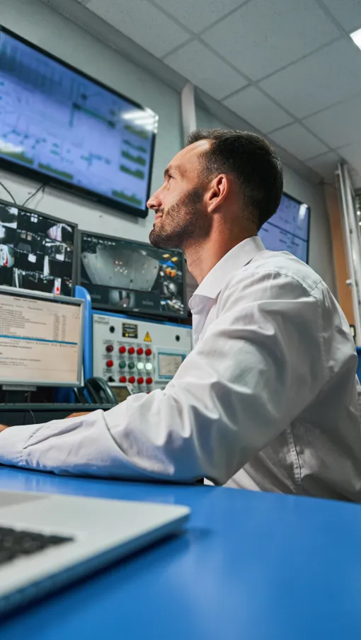a man sitting at a desk with multiple monitors