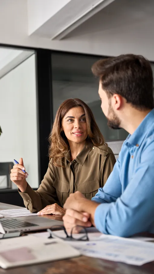 a man and a woman sitting at a table looking at a laptop