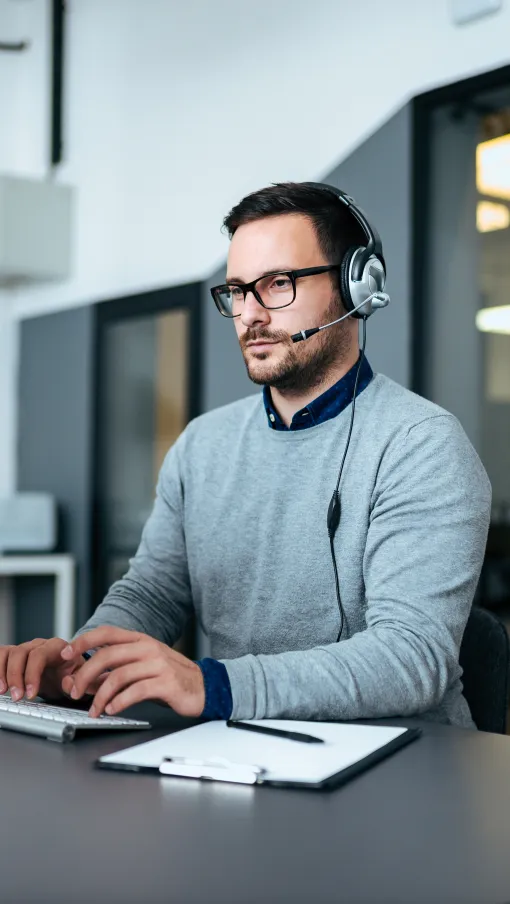 a man wearing headphones and sitting at a desk with a computer