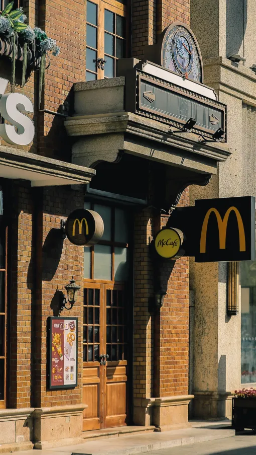 McDonald's restaurant entrance featuring classic brick facade, wooden doors, branded signage, and outdoor menu display.