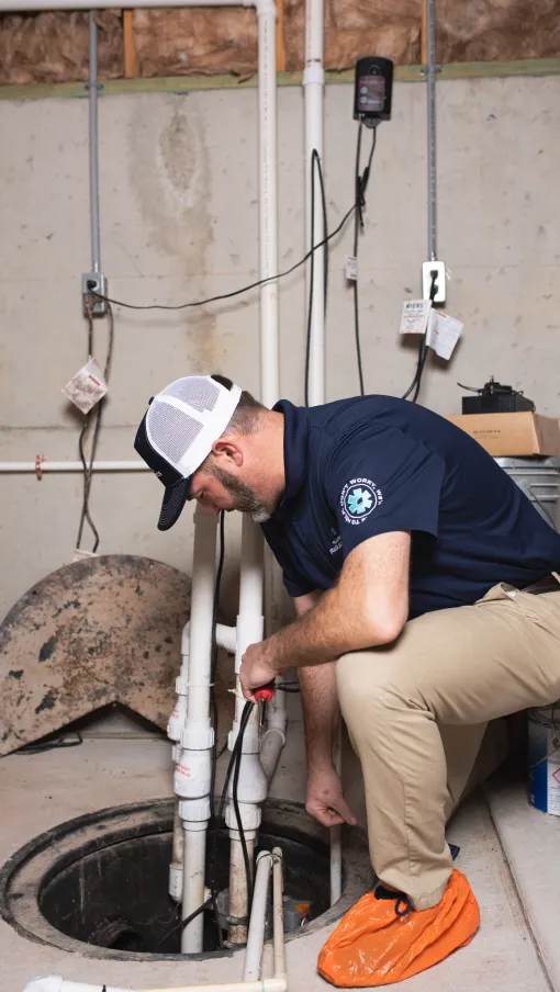 Plumbing Paramedics technician working on a sump pump in a home in Crown Point, IN