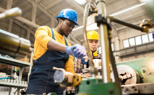 a few men in hardhats working on a machine