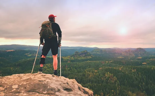 a man with a backpack on a rock overlooking a valley