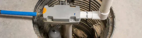Basement sump pump system installed in a concrete pit with pipes and a float switch for water removal.